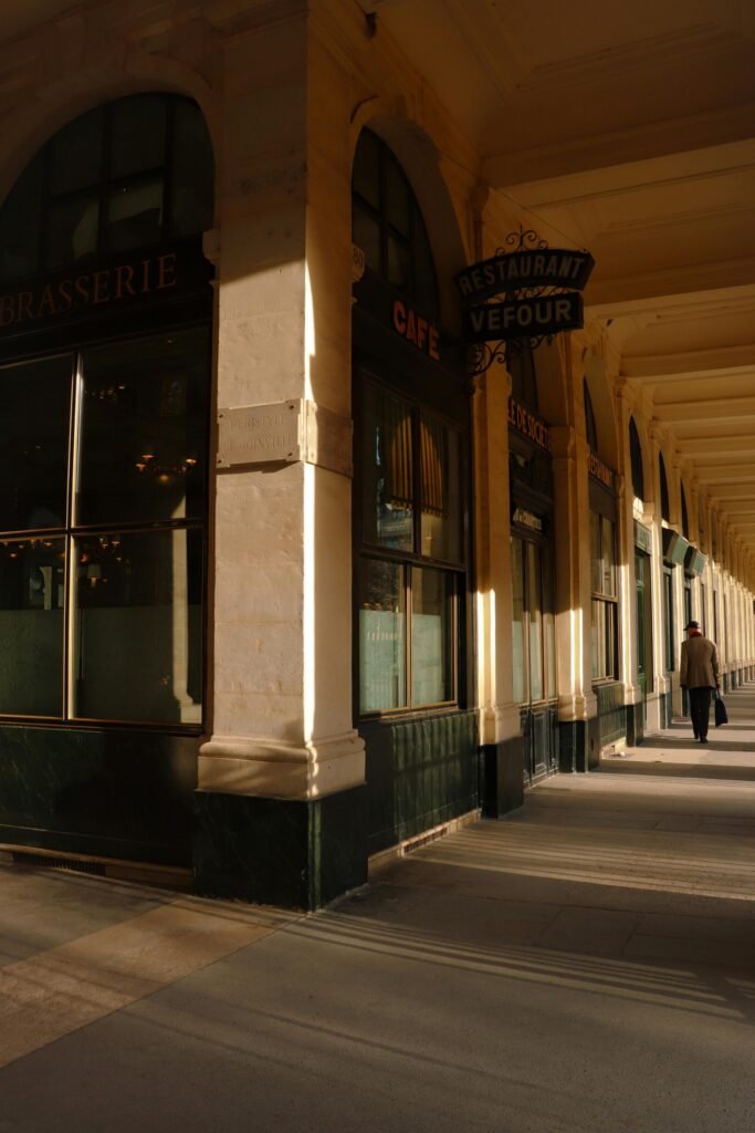 Sunlit corridor of Paris' Palais Royal highlighting classic architecture.