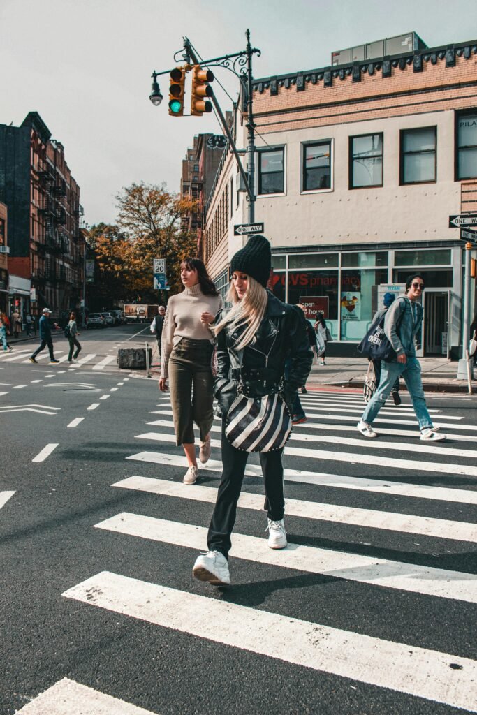People crossing a busy street in a vibrant city setting during the day.